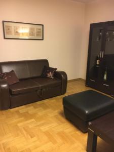 uma sala de estar com um sofá de couro e um repousa-pés em Apartament Alutka em Cracóvia