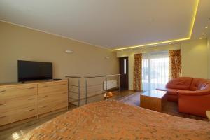 1 dormitorio con 1 cama, TV y sofá en Pas Edgara, en Nida