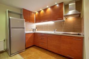 a kitchen with wooden cabinets and a stainless steel refrigerator at Pas Edgara in Nida
