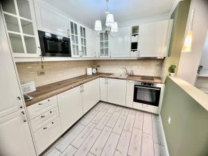 a kitchen with white cabinets and a wooden floor at Sea angel in Burgas City