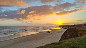 a sunset on a beach with the sun setting at O meo refuxio in Barreiros