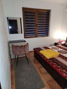 a bedroom with a bed and a chair and a window at PANTELI APART HOUSE in Aheloy