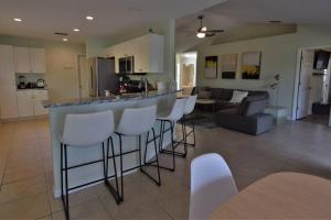 eine Küche und ein Wohnzimmer mit einer Bar mit weißen Stühlen in der Unterkunft Florinda 3bdr/2bth 2car garage with New Pool in Sarasota