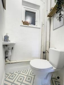 La salle de bains est pourvue de toilettes, d'un lavabo et d'une fenêtre. dans l'établissement Cosy Apartment Brussels - City Center, à Bruxelles