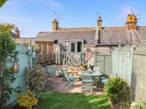 a garden with a table and chairs in front of a house at Higgledy Piggledy Cottage in Swanage
