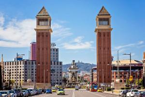 two tall towers in a city with cars on a street at Sweet Inn Plaza Espana Fira in Barcelona