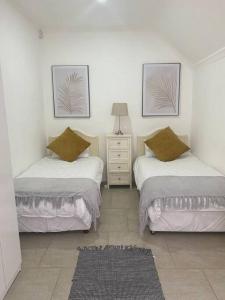 a bedroom with two beds and a dresser with two pictures at “Fyndraai” the home away from home in Gillitts