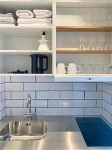 a kitchen with a sink and shelves with glasses at Tiny Guesthouse in Nakskov