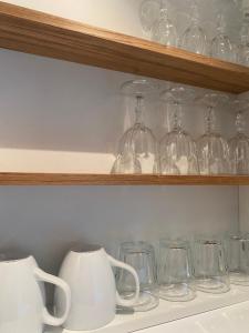 une rangée de verres et de tasses sur une étagère dans l'établissement Tiny Guesthouse, à Nakskov