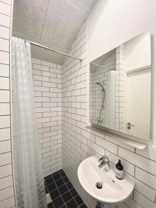 W białej łazience znajduje się umywalka i lustro. w obiekcie Tiny Guesthouse w mieście Nakskov