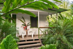 um alpendre de uma casa branca com cadeiras e árvores em Finca D'Elía Lodge em Puerto Limón