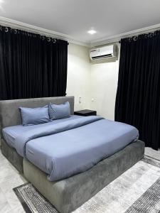 een groot bed met blauwe kussens in een slaapkamer bij Modern City Center 3-Bed Apartment in Abuja