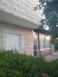 a brick house with a window and bushes at LTD Hadas Garden apartment in Tiberias