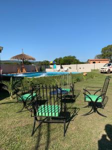 a group of chairs sitting in the grass near a pool at Quinta Coki in Pirayú