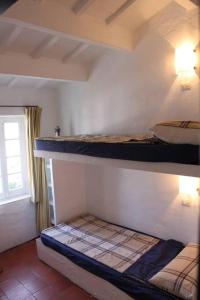 two bunk beds in a room with a window at Casa típica menorquina cèntrica amb encant in Fornells