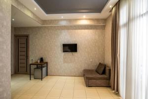a living room with a couch and a television on a wall at Tbilisi Sea Hotel in Tbilisi City