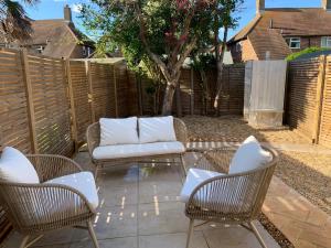a patio with two chairs and a couch and a fence at sea side cottage near beach in West Wittering