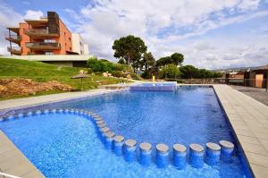 a large swimming pool with blue water in front of a building at Pretty garden apartment next to a charming beach in Lloret de Mar