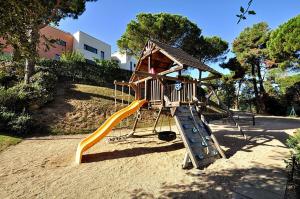 a playground with a slide and a play structure at Pretty garden apartment next to a charming beach in Lloret de Mar