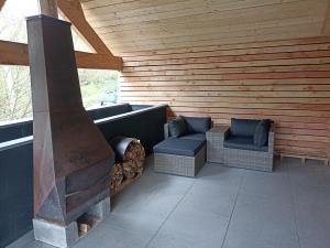 an outdoor patio with two chairs and a fireplace at Toit & Moi. in Stoumont
