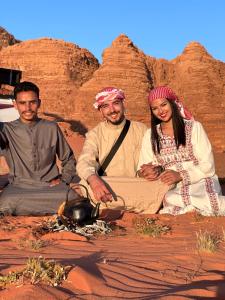 Un groupe de trois personnes assises dans le désert dans l'établissement Wadi Rum Oryx Hostel & Tours, à Wadi Rum