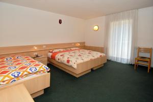 a hotel room with two beds and a chair at Hotel Zanon in Ziano di Fiemme