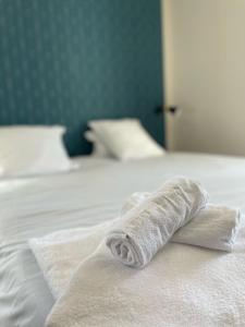 una toalla encima de una cama blanca en Appart'Hôtel Sous Les Pins en Martigues