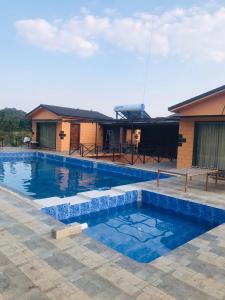 a large swimming pool in front of a house at Whispering Woods Chalet in Sasan Gir