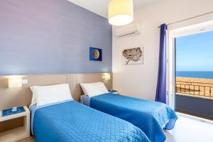 two beds in a room with a view of the ocean at Appartamento Moderno con vista mare in Castelsardo