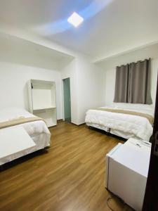 1 dormitorio con 2 camas y suelo de madera dura en Hotel Santorine Prime - By UP Hotel - Próximo a Fundação Cultural Carlos Drummond Andrade, en Itabira
