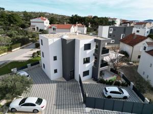 a white house with two cars parked in front of it at Apartman Petra in Brodarica