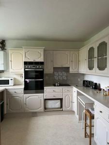 a kitchen with white cabinets and black appliances at A taste of Camberwell & Dulwich! in London