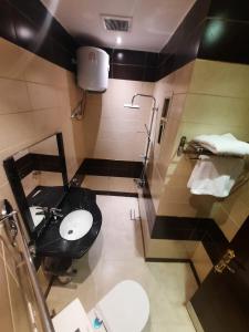 baño con aseo negro y lavamanos en اجنحة الماسم المخدومة -حى غرناطة en Riad