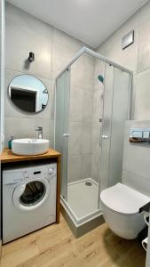 ein Bad mit einer Dusche, einem WC und einer Waschmaschine in der Unterkunft Turkusowy Sopot in Sopot