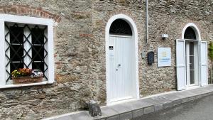 un edificio in pietra con due finestre e una porta bianca di B&B Gronda Via Vandelli a Massa