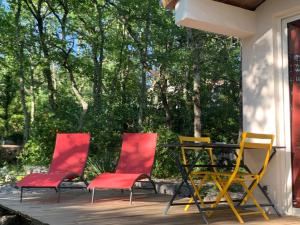 three chairs and a table on a deck with trees at Le Mazet, studio avec terrasse et spa in Saint Alban Auriolles