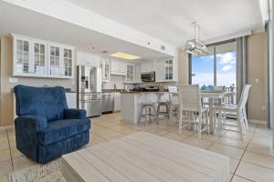 a living room with a blue chair and a kitchen at Phoenix VIII 1406 in Orange Beach
