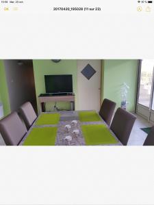 comedor con mesa con sillas y TV en Maison de Jade en Noailles