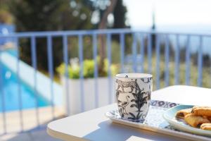 a coffee cup sitting on a table with a plate of food at Les Volets Bleus in Spéracèdes