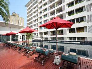 曼谷的住宿－素坤逸通羅中心站酒店，游泳池旁的一排椅子和遮阳伞