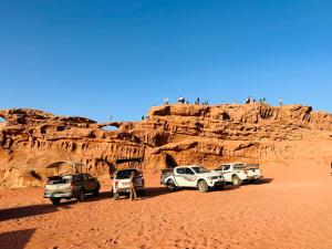 un groupe de véhicules garés dans le désert dans l'établissement Wadi Rum Oryx Hostel & Tours, à Wadi Rum