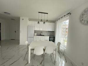 - une salle à manger blanche avec une table et des chaises blanches dans l'établissement Seaside Apartment, à Gdańsk