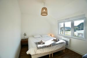ein weißes Schlafzimmer mit einem Bett und einem Fenster in der Unterkunft Le Logis de la Mer in Concarneau