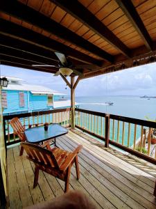 a table and a bench on a deck with the ocean at Aqua Lounge Bar & Hostal in Bocas del Toro