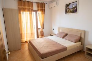 a bedroom with a large bed and a window at Villa Dei Limoni in Durrës