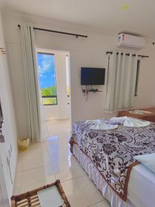 1 dormitorio con cama, ventana y TV en Pousada Lá na Praia Maragogi, en Maragogi