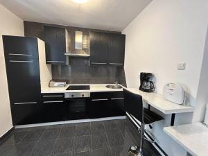 eine kleine Küche mit schwarzen Schränken und einem Waschbecken in der Unterkunft Apartment Decumana in Krk