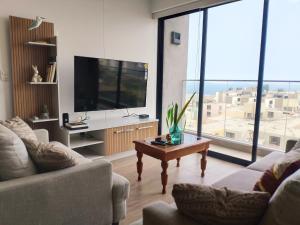 a living room with a television and a coffee table at LOFT EN LIMA VISTA AL OCEANO - ¡Nuevo! Depa - Magdalena del Mar - in Lima