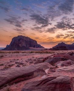 a sunset in the desert with rocks and mountains at Wadirum Zeid camp in Wadi Rum