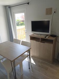 a living room with a dining table and a television at Le panorama in Guérande